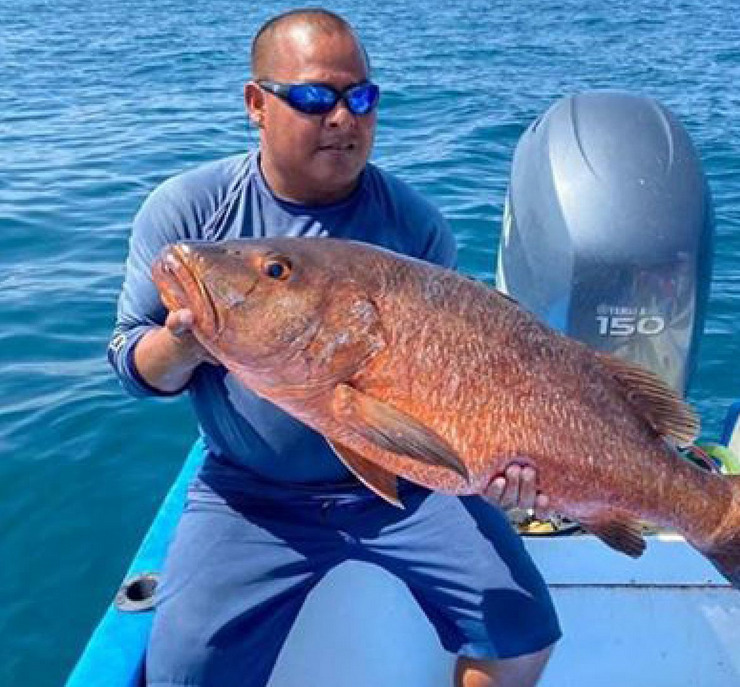 Captain Elier Duran holding a large snapper aboard Soleil